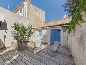 A wooden deck with two lounge chairs, a potted plant with pink flowers, and a blue door. - 350 m from the Main Beach - House 4 adt/ 2 chd (Les Sables-d´Olonne)
