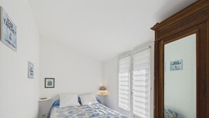 Ein Schlafzimmer mit einem Bett, einem Nachttisch, einer Lampe, einem Kleiderschrank und einem Fenster mit Jalousien.