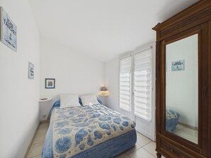 A bedroom with a bed, a nightstand, a lamp, a wardrobe, and a window with blinds. - 350 m from the Main Beach - House 4 adt/ 2 chd (Les Sables-d´Olonne)