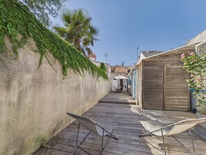 A narrow wooden deck with two white folding chairs, a concrete wall with green ivy, and a building with a tiled roof in the background. - 350 m from the Main Beach - House 4 adt/ 2 chd (Les Sables-d´Olonne)