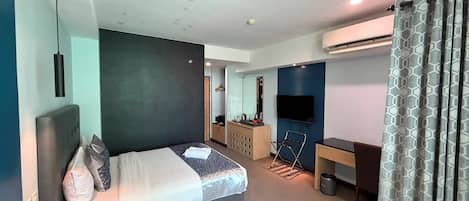 Quarto de hotel moderno com cama, escrivaninha e televisão.
