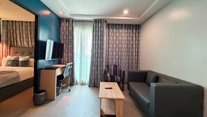Ein Hotelzimmer mit Bett, Schreibtisch mit Stuhl, einer Couch, einem Couchtisch und einem Fernseher.