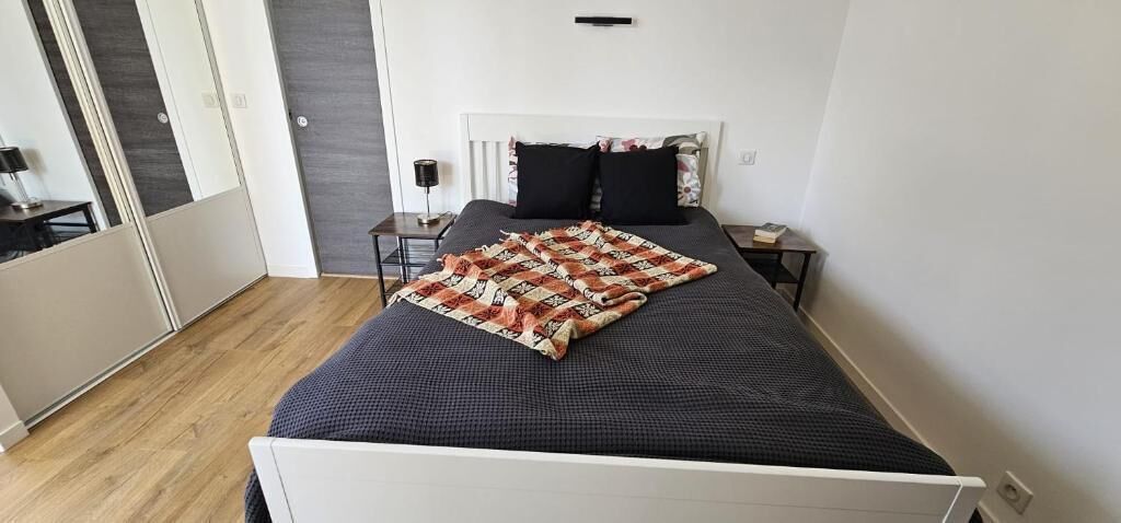 Une chambre à coucher avec un lit, une table de chevet, une lampe et une porte.
