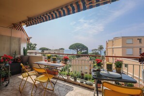 A balcony with a table and chairs, potted plants, and a view of the sea. - Cannes Sea View Beach Private Room (Cannes)