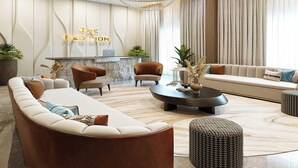 Un área de recepción moderna con mostrador, sofás, sillones y una araña.
