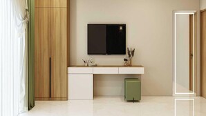 Habitación moderna con televisión de pantalla plana en la pared, un armario de madera, un mueble verde y una puerta a la derecha.