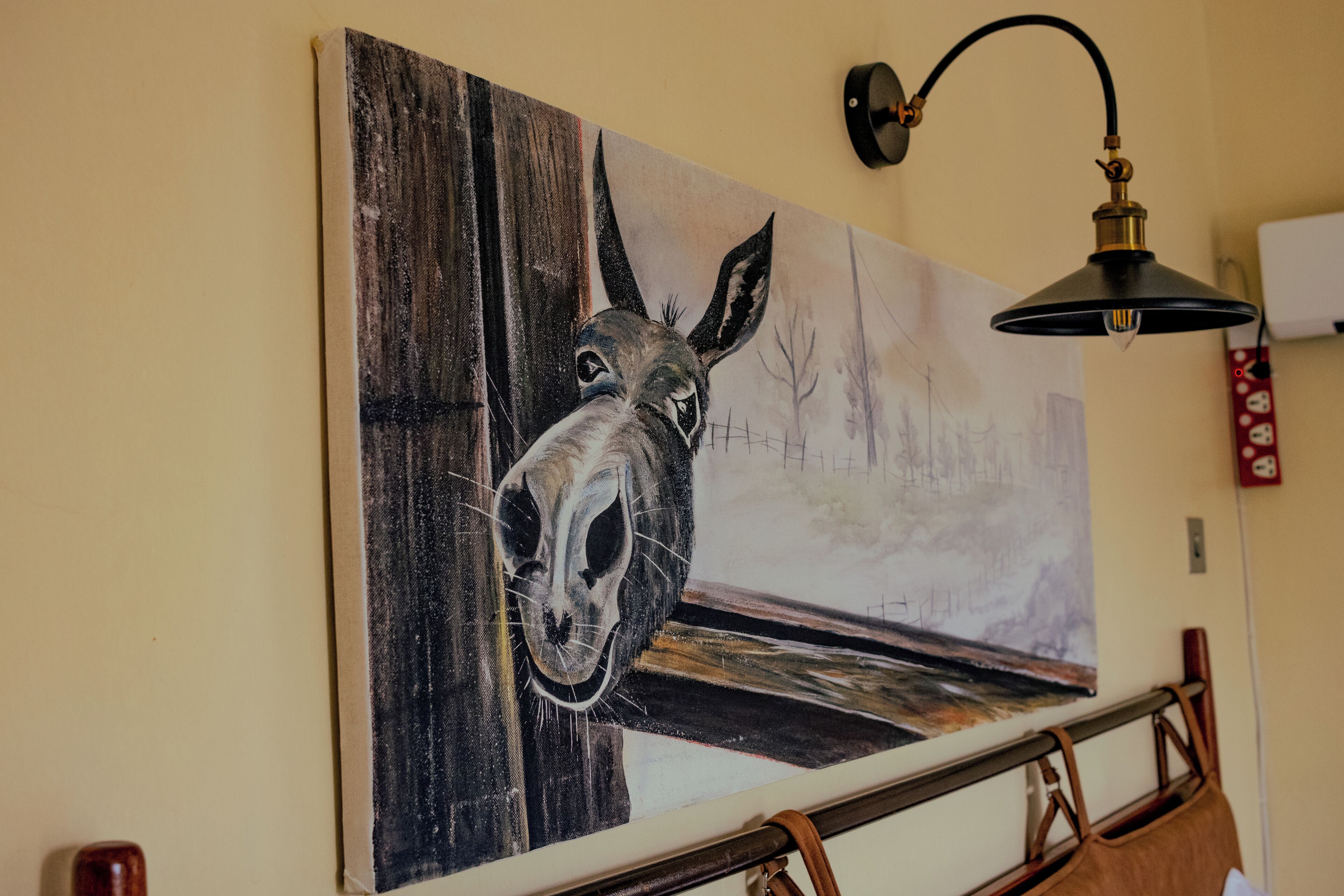 A painting of a horse's head on a wall, a lamp, and a wooden railing.