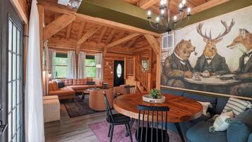 Interior acogedor de una cabaña de troncos con comedor, sofá y un mural de osos.