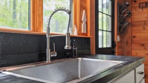 Una cocina con un grifo moderno, salpicadero de azulejos negros y armarios de madera.