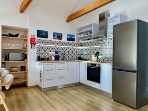 A modern kitchen with white cabinetry, a stainless steel refrigerator, and a patterned backsplash. - Renovated fisherman house sleeping 4 with terrace, BBQ & magnificent views (Horta)