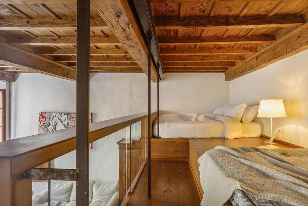 Une pièce avec un plafond en bois, un lit avec une literie blanche, une table de chevet avec une lampe et une fenêtre donnant sur un paysage agréable.