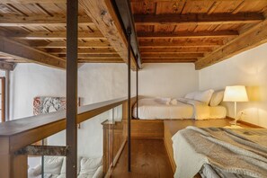 A room with a wooden ceiling, a bed with white bedding, a bedside table with a lamp, and a window with a view. - Via Maggio 10 – Historic Loft in Oltrarno  (Florence)