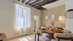 A dining area with a round table, chairs, a vase with flowers, and a lamp. - Charming Apartment in Le Marais Center of Paris (Paris)