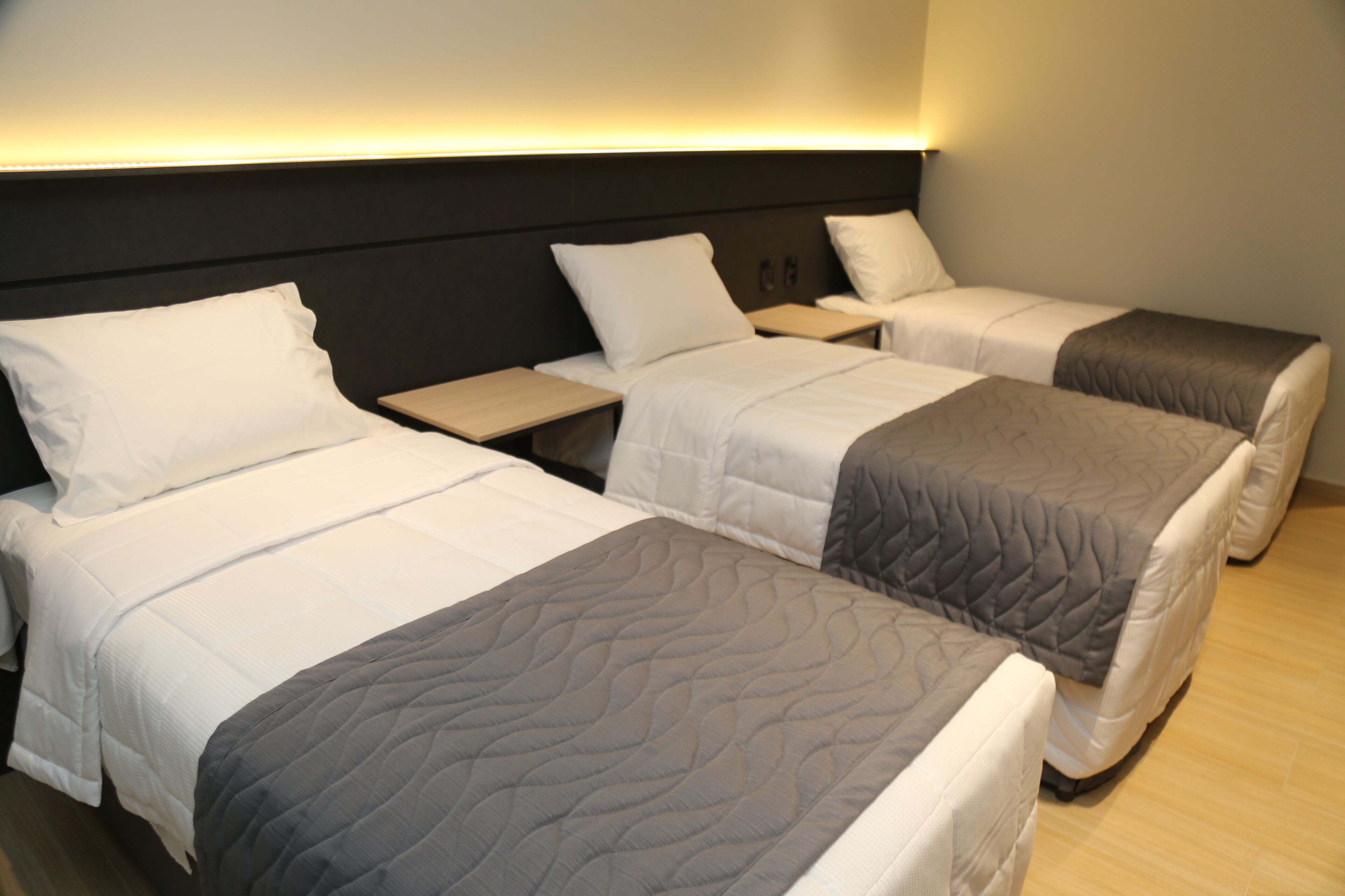 Habitación de hotel con dos camas individuales, una mesita de noche y una lámpara fijada a la pared.