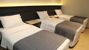 Habitación de hotel con dos camas individuales, una mesita de noche y una lámpara fijada a la pared.