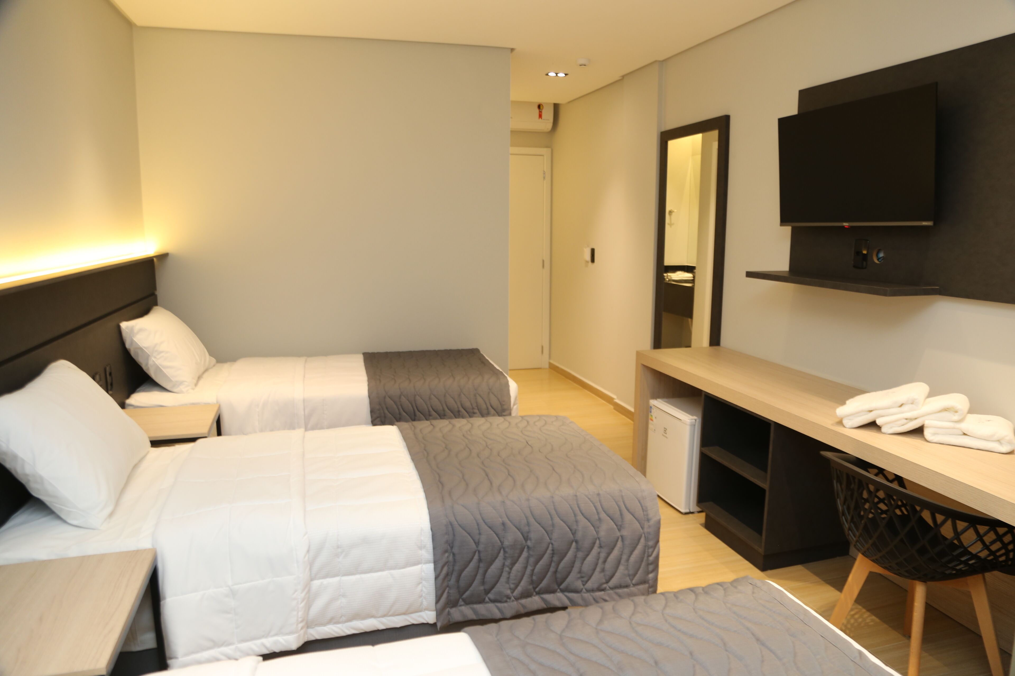 Een hotelkamer met twee bedden, een bureau, een televisie en een zithoek.