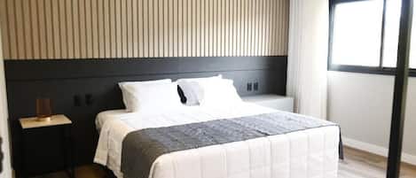 Un dormitorio moderno con cama, mesitas de noche y una ventana con cortinas.