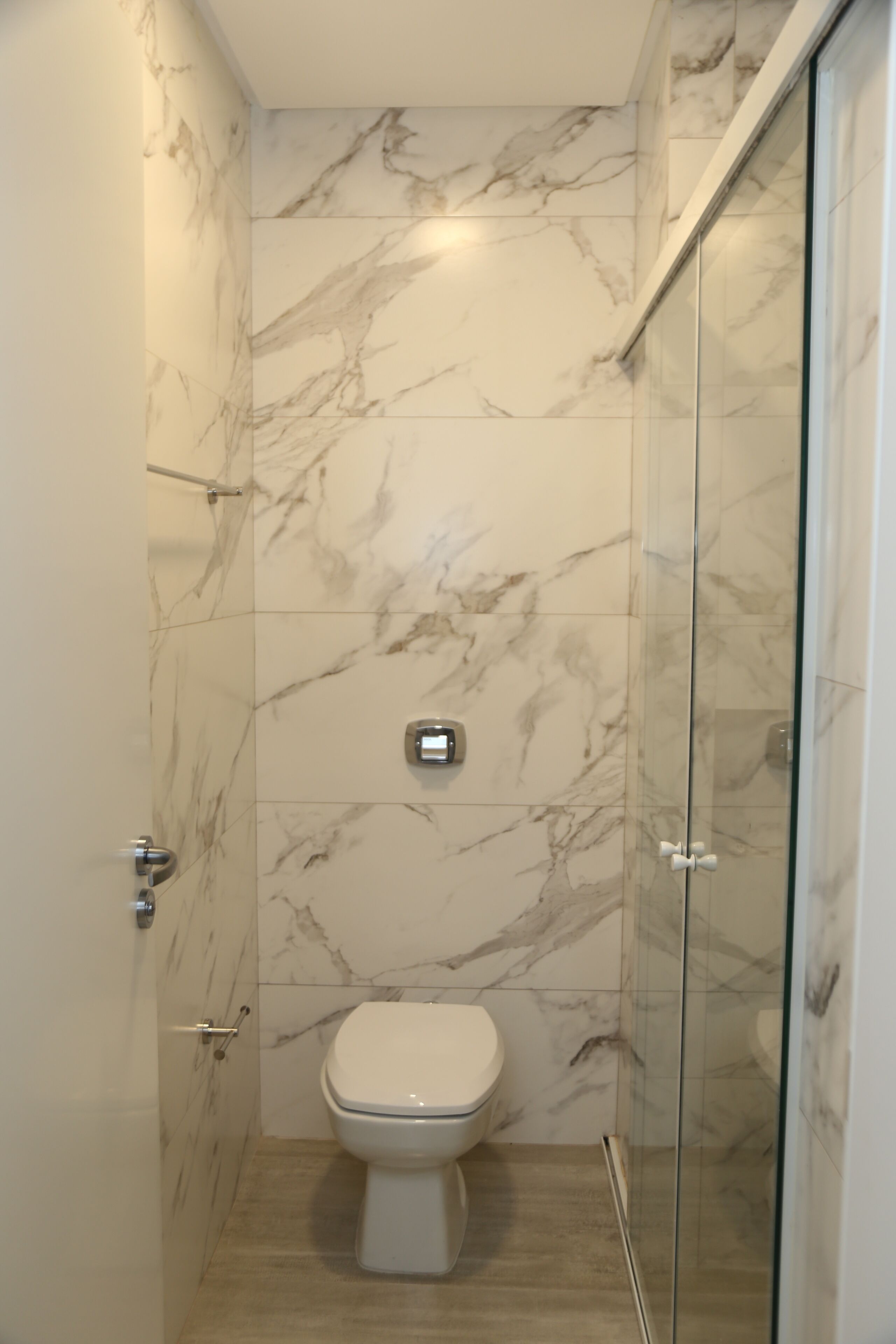 A bathroom with a toilet, a shower, and marble walls.