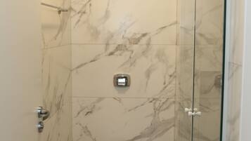 A bathroom with a toilet, a shower, and marble walls.