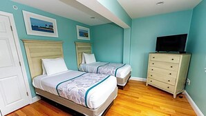 A bedroom with two beds, a dresser, and a television. - Edgewater Beach Resort (Dennis Port)