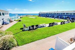 Un hotel con un césped bien cuidado, zona de estar al aire libre y vistas al océano.