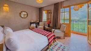 Hotellihuone, jossa on suuri sänky, työpöytä, tuoli, ikkuna, josta on näkymä, ja parveke.