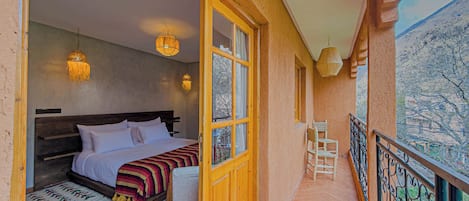 Un dormitorio con cama, lámparas de noche, ventana y balcón con barandilla.