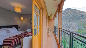 Un dormitorio con cama, ventana y balcón con vistas a las montañas.