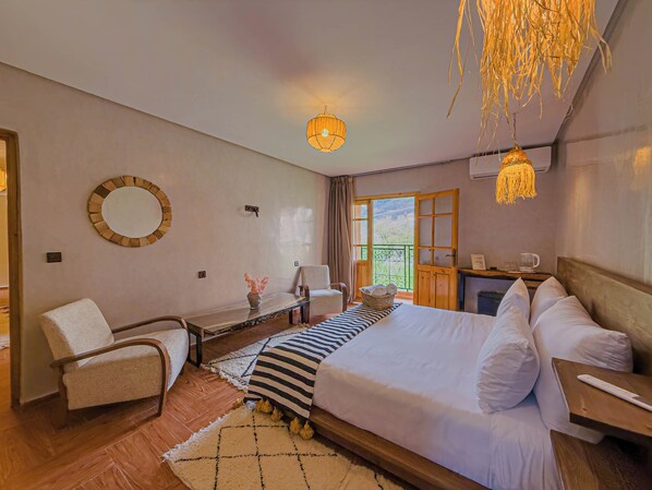 Ett hotellrum med en säng, en stol, ett skrivbord, en spegel och utsikt över omgivningarna.