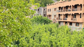 A hillside building with multiple balconies and a lush green foreground.