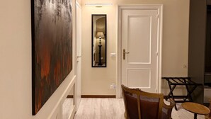 Um corredor com uma porta branca, um espelho emoldurado e um quadro na parede.