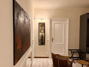 A hallway with a white door, a framed mirror, and a painting on the wall. - Luxurious Apartment on Via Frattina (Roma)