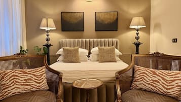 A hotel room with a bed, two chairs, a small table, and two wall-mounted lamps.