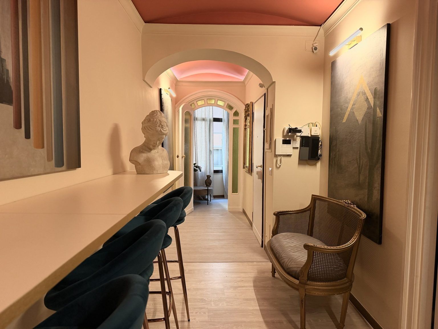 A hallway with a bar area, a sculpture, and a painting.