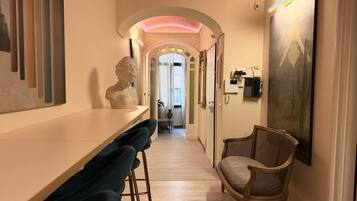 A hallway with a bar area, a sculpture, and a painting.