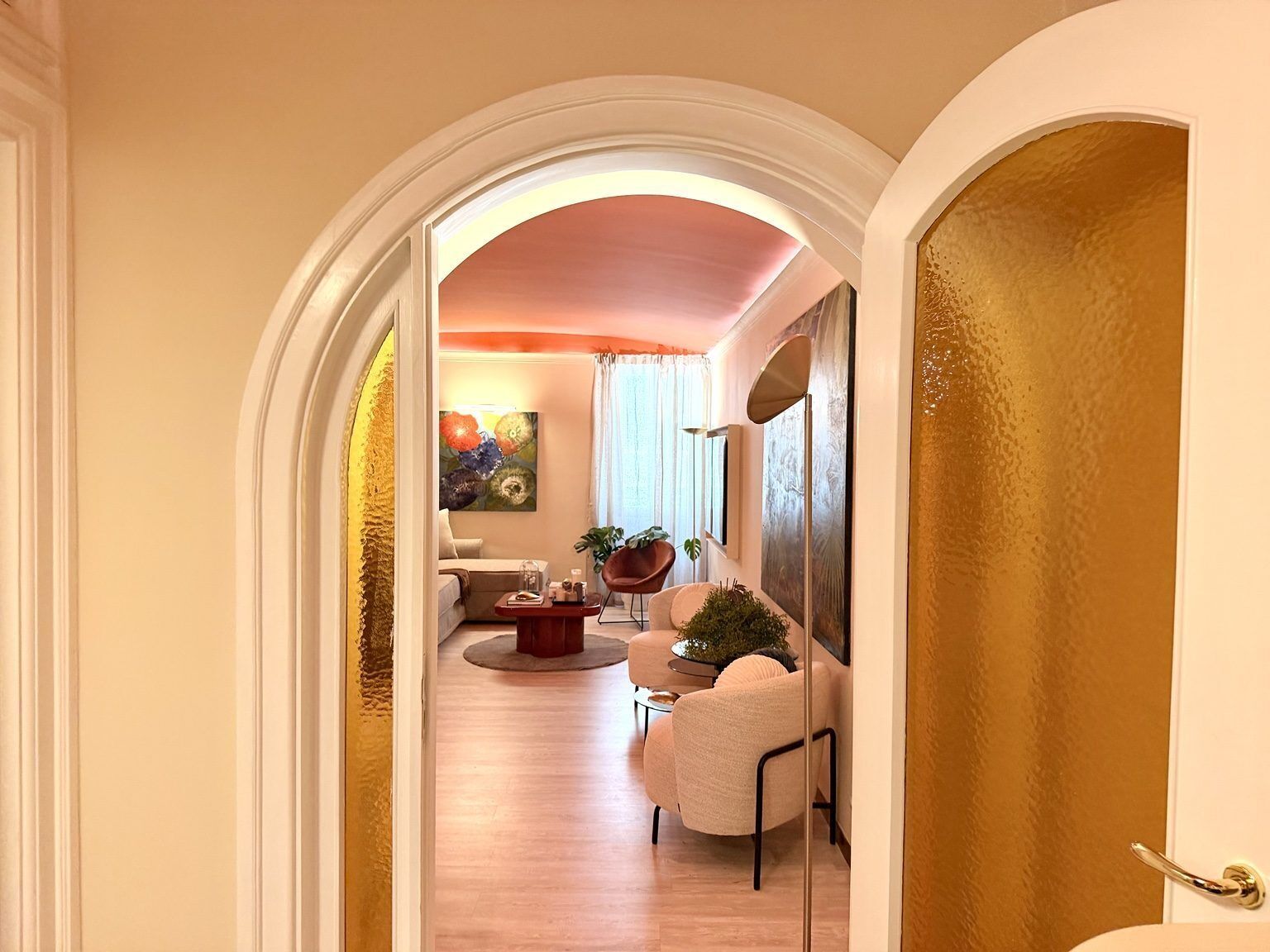 A hallway leading to a living area with a sofa, a coffee table, and a potted plant.