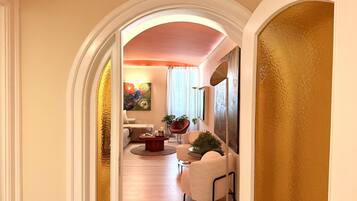 A hallway leading to a living area with a sofa, a coffee table, and a potted plant.