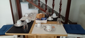 A dining table set with white and floral-patterned tableware, a wicker basket, and a coffee bag.