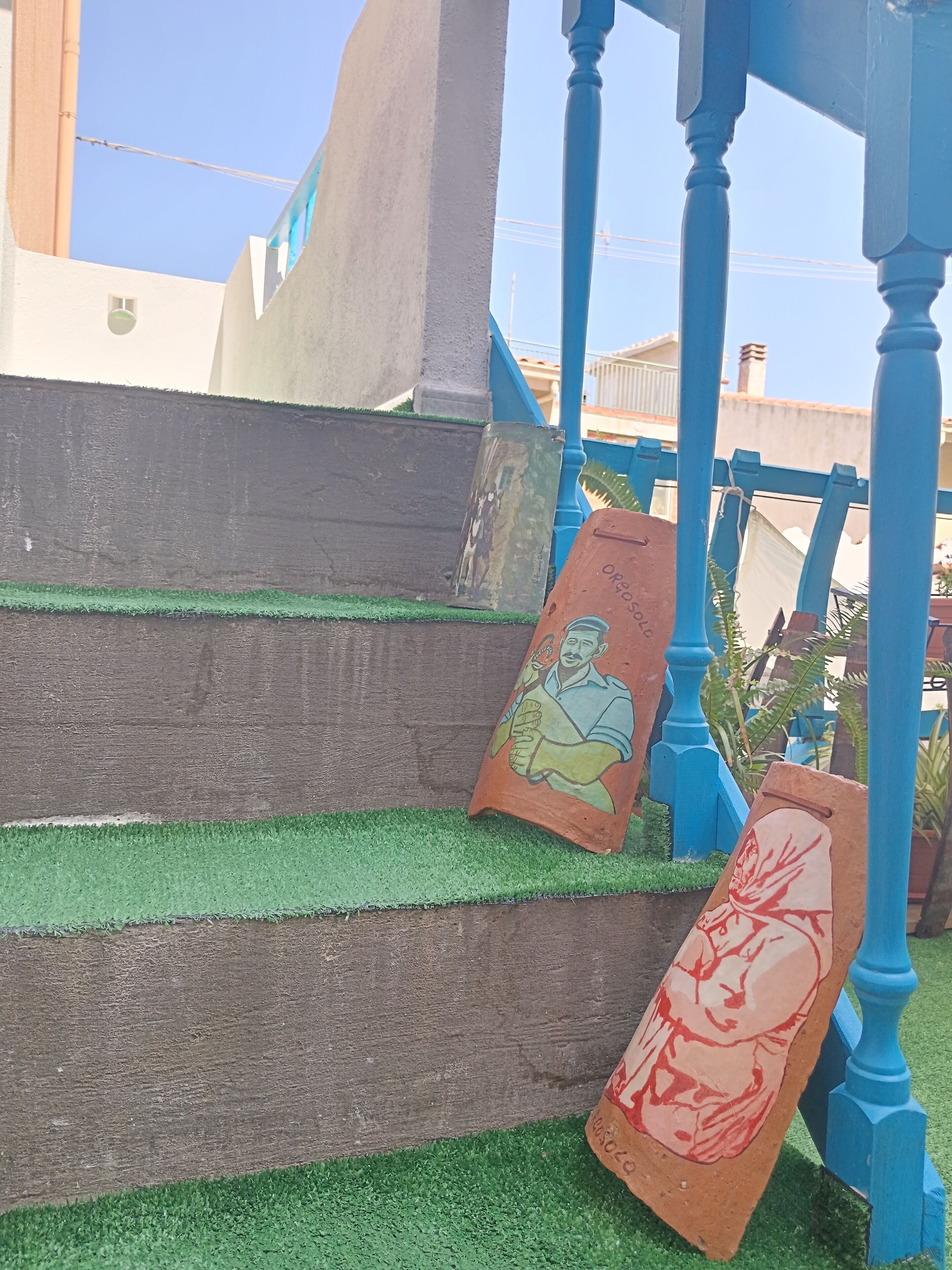 Un conjunto de escaleras con césped artificial verde que conducen a una estructura azul con columnas ornamentadas.