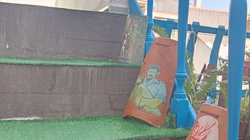Un conjunto de escaleras con césped artificial verde que conducen a una estructura azul con columnas ornamentadas.