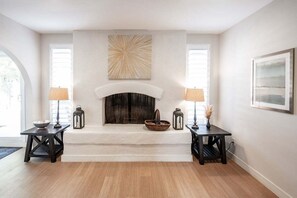 Ein Zimmer mit Kamin, zwei Nachttische mit Lampen und einem gerahmten Kunstwerk darüber.