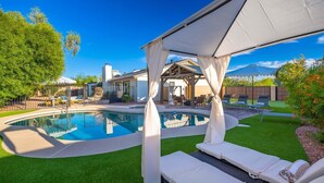 En baghave med swimmingpool, liggestole og en overdækket terrasse.