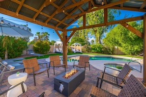 Eine Terrasse im Freien mit Feuerstelle, Liegestühlen und Pool.