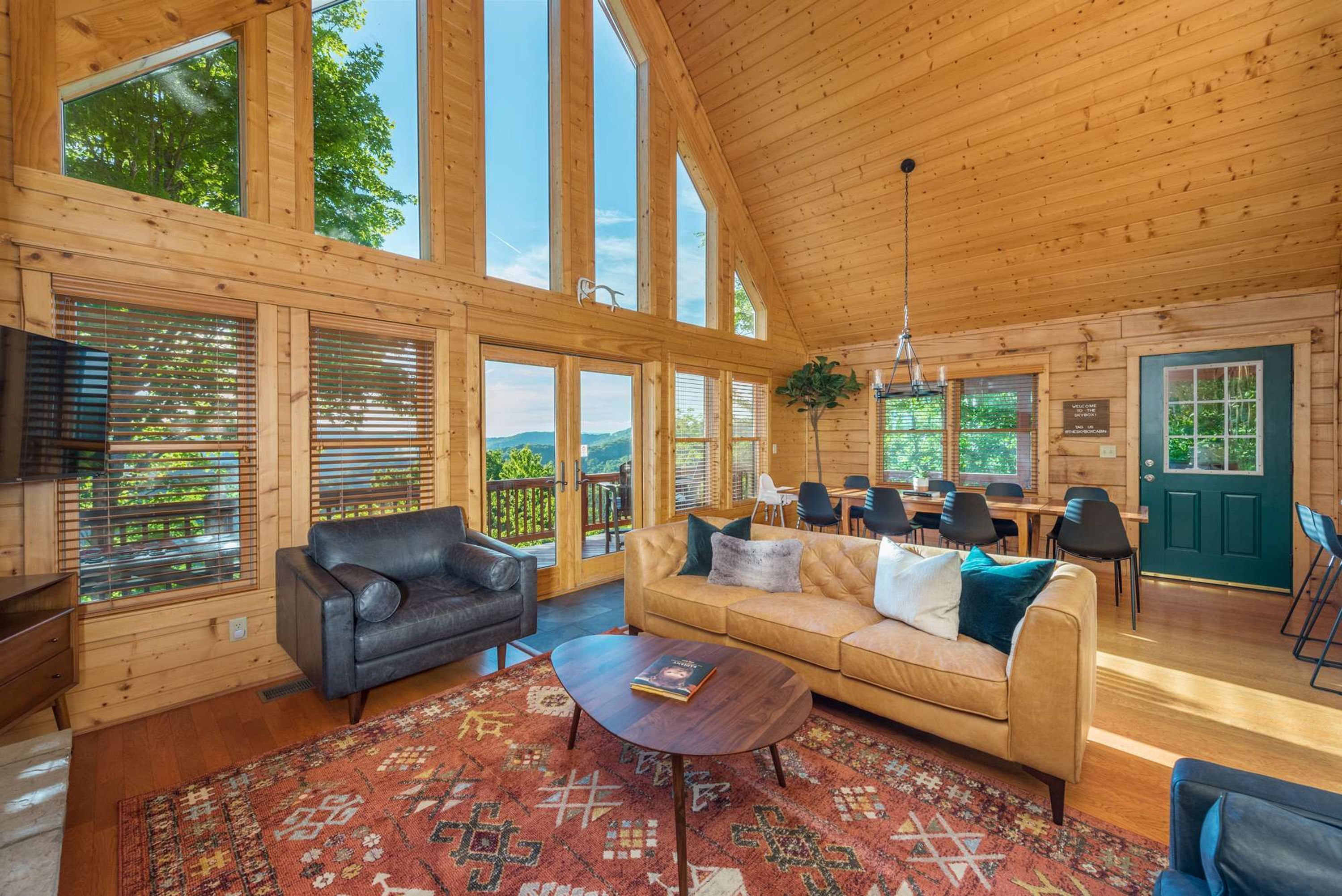 A spacious living area with a large window, a sofa, a coffee table, and a dining area with chairs.