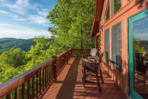 A wooden deck with a view of a forested mountain range.