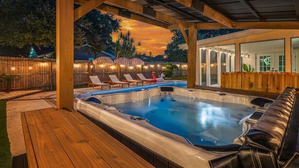 A hot tub under a wooden pergola with a view of a house and a sunset. - Beach Bliss Movie Theater Putt Putt Pool (Largo)