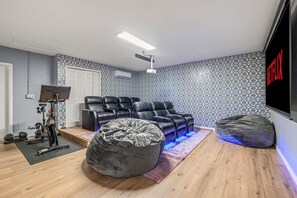 A home theater room with a large flat-screen TV, reclining leather chairs, a projector, and a sound system. - Beach Bliss Movie Theater Putt Putt Pool (Largo)
