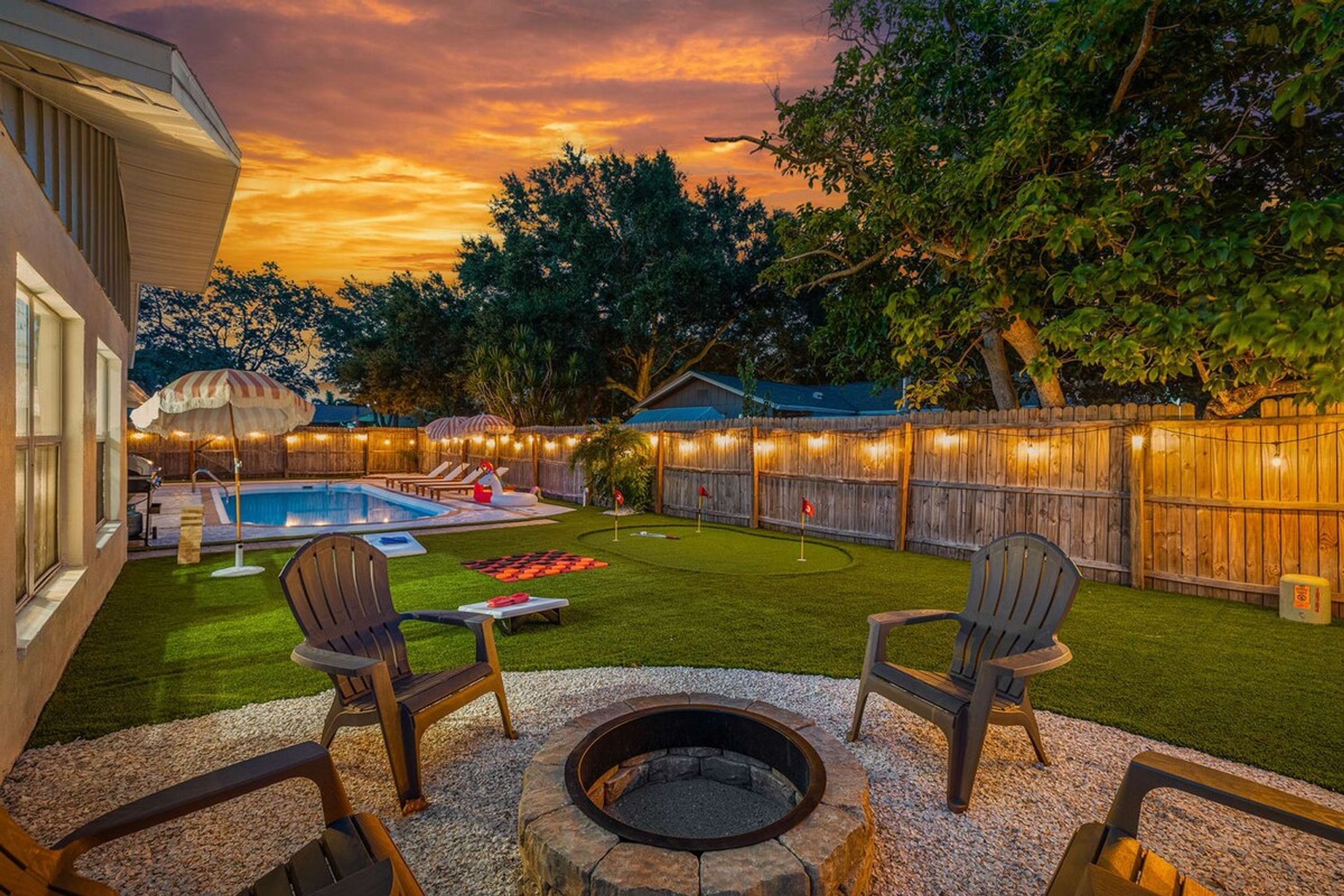 A backyard with a swimming pool, a fire pit, and outdoor seating.