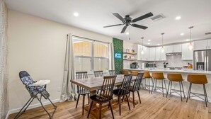 A modern kitchen with a dining area, wooden flooring, and a ceiling fan. - Beach Bliss Movie Theater Putt Putt Pool (Largo)