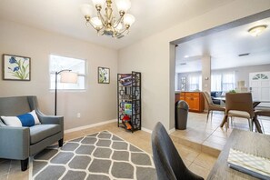 A living room with a sofa, a rug, a chandelier, and a bookshelf. - Monthly Rental Comfy Beds Great for Remote Work (Clearwater)